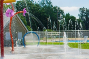 A splash pad with various water features spraying water on a sunny day.